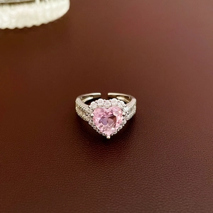 Pink heart-shaped zircon open ring with side diamonds on a premium leather background