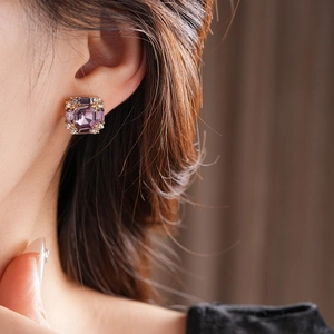 Macro shot of square purple gemstone stud earrings with crystal halo on earlobe