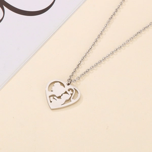 Silver heart necklace with hollow mother and child silhouette on beige surface