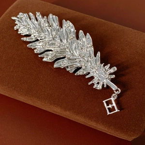 Macro detail of silver feather brooch with white zircon inlay on brown velvet case