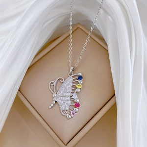 Detailed view of silver butterfly necklace with colorful gems on a beige jewelry box