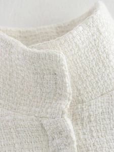 Detailed macro view of white tweed fabric texture and neckline craftsmanship on the cape
