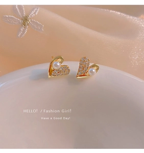 Macro shot of heart earrings with pearls and pavé zircons on soft silk background