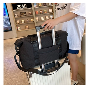 Black quilted travel bag with back trolley sleeve shown on a suitcase in a bookstore