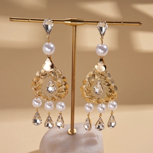 Close-up of vintage hollow drop earrings with pearls and crystals on a display stand