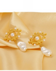 Detail of 18K gold evil eye earrings with baroque pearl drop on silk background