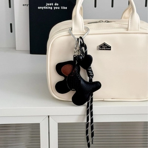 Minimalist black leather dog bag charm with heart pendant and striped lanyard on tote