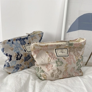 Détail de trousses à maquillage en jacquard avec motifs floraux et fermeture éclair