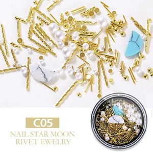Macro detail of gold rivets, white pearls, and marble moon nail art accessories C05