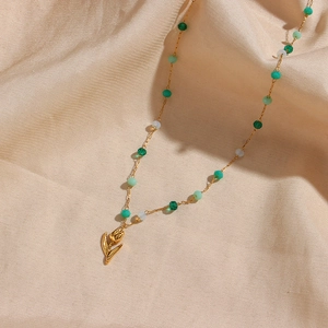 Collier élégant avec pendentif tulipe et perles colorées sur fond de soie champagne