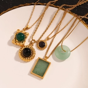 Flat lay of vintage 18K gold plated necklaces with green and black natural stone pendants