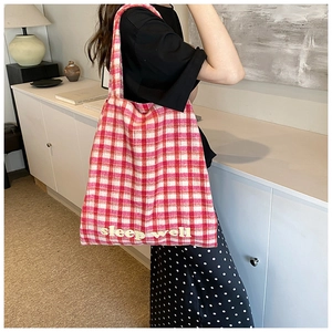 Close-up of red and white checkered knit tote bag with sleep well embroidery