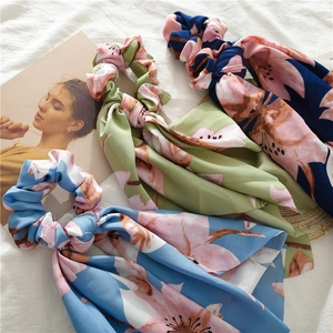 Detailed close-up of floral satin scrunchies with streamers on a white fabric background