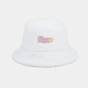 Détail d'un bob en fausse fourrure blanche avec broderie Happy et patch étoile rose