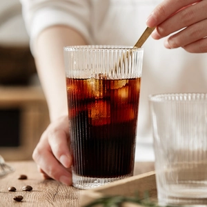 Minimalist transparent ribbed glass cup for coffee and cold drinks on a wooden table