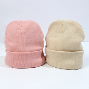 Close-up of pink and beige knitted hats showing fine texture and ribbed cuff detail