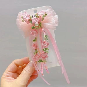 Detail of pink chiffon hair clip with floral embroidery and elegant long ribbons