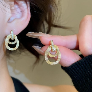 Dettaglio orecchini a doppio cerchio placcati oro 18k con cristalli e finitura testurizzata