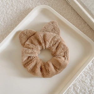 Detail of plush brown scrunchie with cute animal ears in a soft aesthetic setting