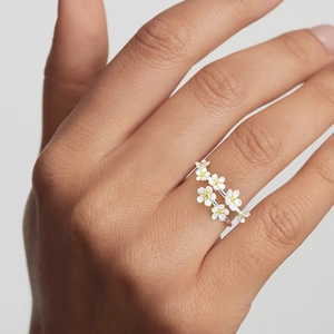 Close-up of S925 sterling silver floral ring with small yellow flowers on female hand