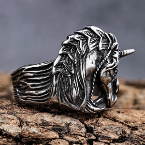 Retro stainless steel unicorn ring with intricate punk style carvings on a wood surface