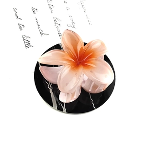 Detail of translucent resin plumeria flower hair claw in gradient orange-pink finish
