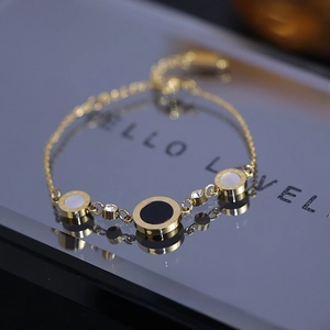 Detailaufnahme des goldenen Armbands mit schwarz-weißen Anhängern und Zirkonia-Steinen