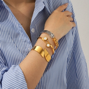 Mixed metal star bracelets and Roman numeral cuff stacked on wrist in stainless steel