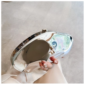 Detail of silver irregular metal clutch with mirror finish and cylindrical top clasp