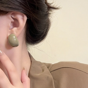 Close-up of olive green resin geometric earring worn by model in brown suit