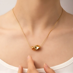 Macro view of gold minimalist twisted geometric pendant on a delicate snake chain