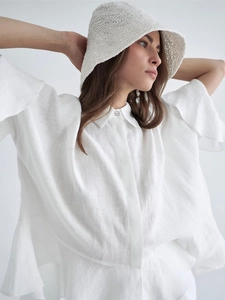 Détail d'une chemise en lin blanc avec poignets à volants et chapeau au crochet