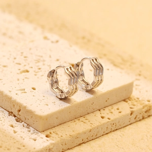Close-up of S925 silver wave hoop earrings on a textured stone display board