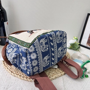 Ethnic style canvas backpack featuring white elephant print and brown woven shoulder straps