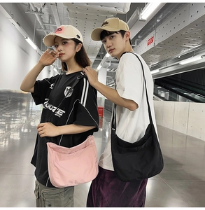 Large casual crossbody bags in black and pink worn by couple on adjustable straps