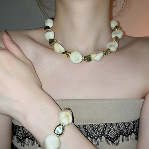 Close-up of white irregular acrylic beads and gold necklace set on a female model