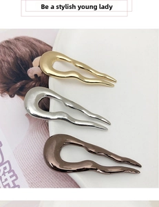 Three wave-shaped metal U-shaped hairpins in gold, silver and black finish on a white plate