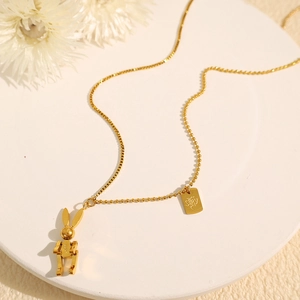 Mechanical rabbit pendant necklace in gold finish with engraved LUCK bar on white display