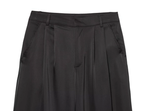 Detail showing the waist pleats and silky texture of black satin trousers with side pockets