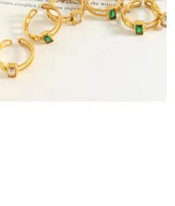 Detail of gold twisted rings featuring emerald cut green and white zircon crystals