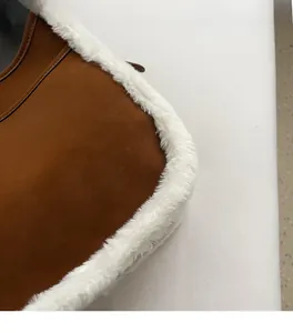 Detailed side view of brown leather underarm bag with white faux fur trim and fine texture