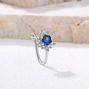 Macro view of snowflake nose stud featuring blue center stone and silver plating