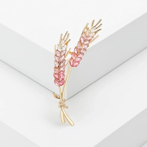 Macro shot of gold wheat ear brooch featuring pink and clear crystal gradient detail