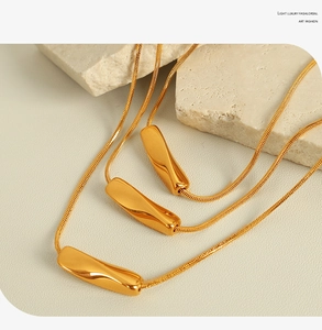 Detail of gold snake chain necklace with a minimalist twisted rectangle geometric pendant