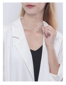 Close-up of geometric S925 silver necklace with sparkling zircon on a model in white blazer