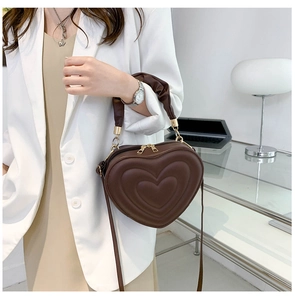 Detail of dark brown heart-shaped bag with embossed texture and gold metal hardware