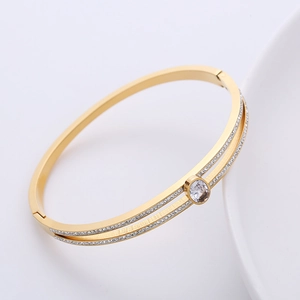 Double row crystal stainless steel bangle with an oval zircon centerpiece and gold plating