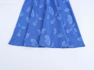 Détail de la robe courte bleue avec broderie florale texturée et tissu de l'ourlet plissé