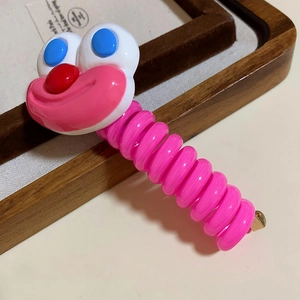 Detail shot of dopamine pink telephone wire hair tie with cute funny cartoon face accent accessory.