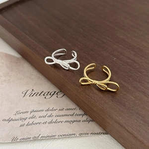 Detail of vintage bow open rings in gold and silver finish on a wooden tray